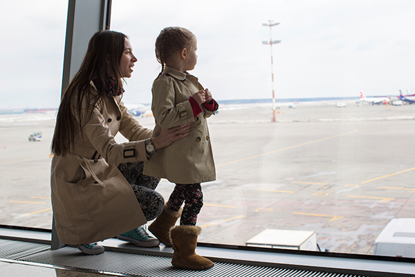 Mom and Child Looking Out Airport Window at Parked Airplanes