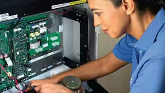 A female maintenance worker operating on a control panel