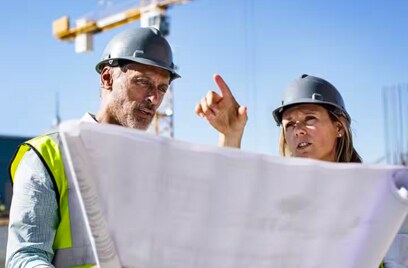 Man and woman analyzing a blueprint at a construction site
