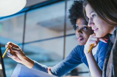 Two businesswomen looking at a laptop and talking
