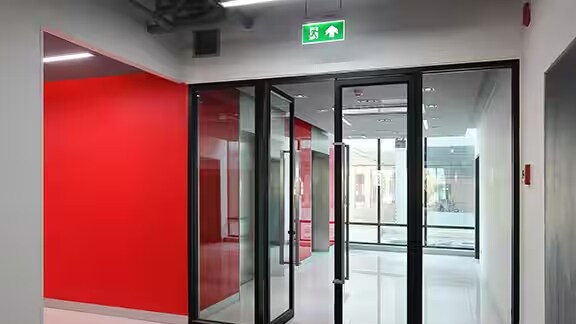 A glass emergency exit door of a building next to a corridor